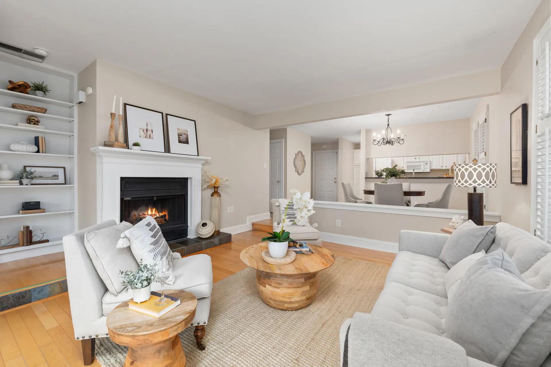 A staged living room with a fireplace, open to the dining room and kitchen