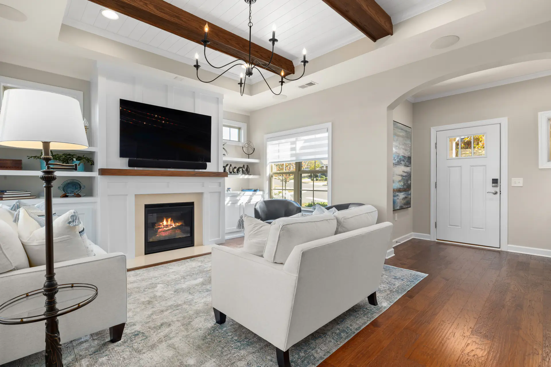 A living room with a gas fireplace, built-in shelves and hardwood floors