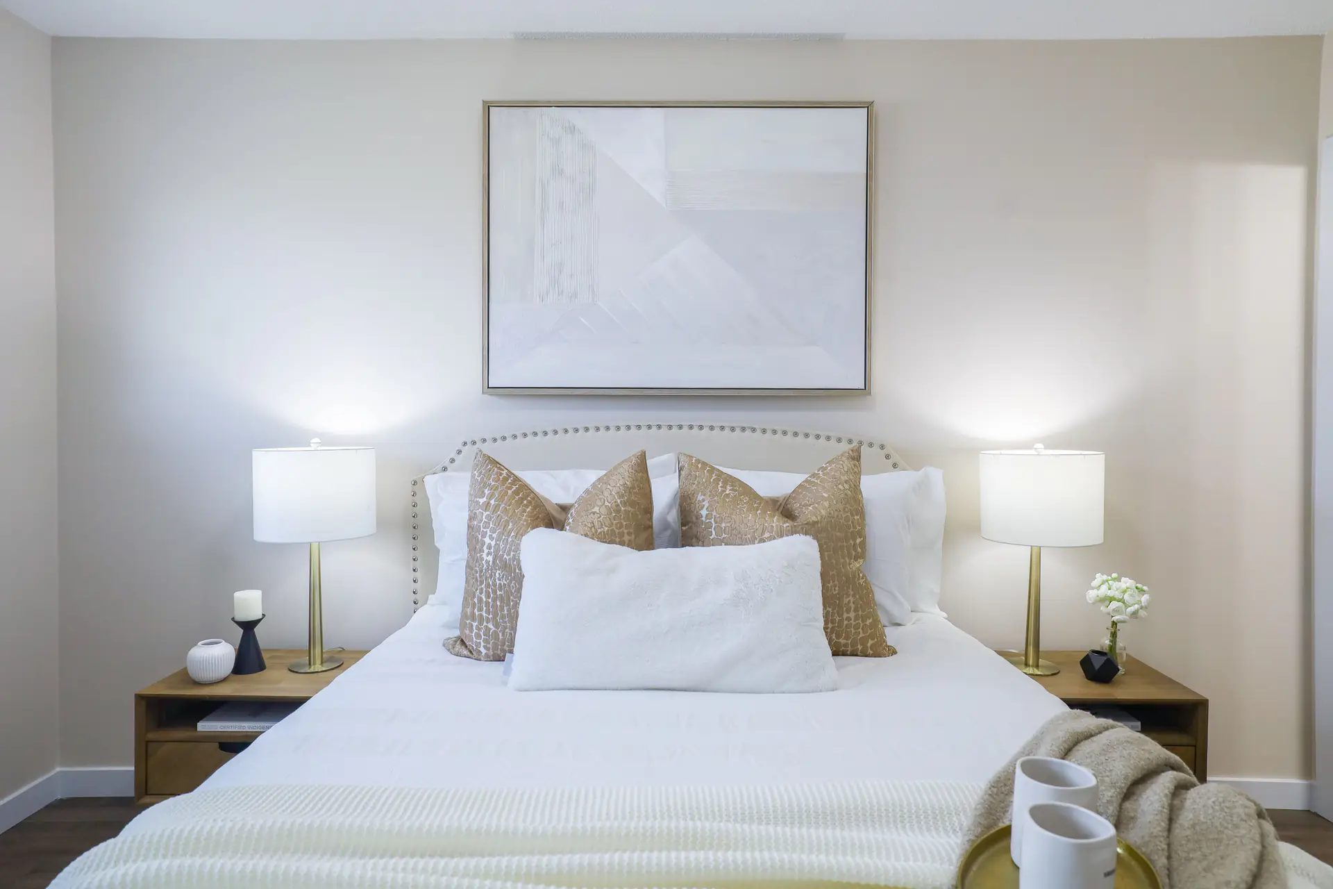 A staged bedroom with a tufted headboard and matching lamps