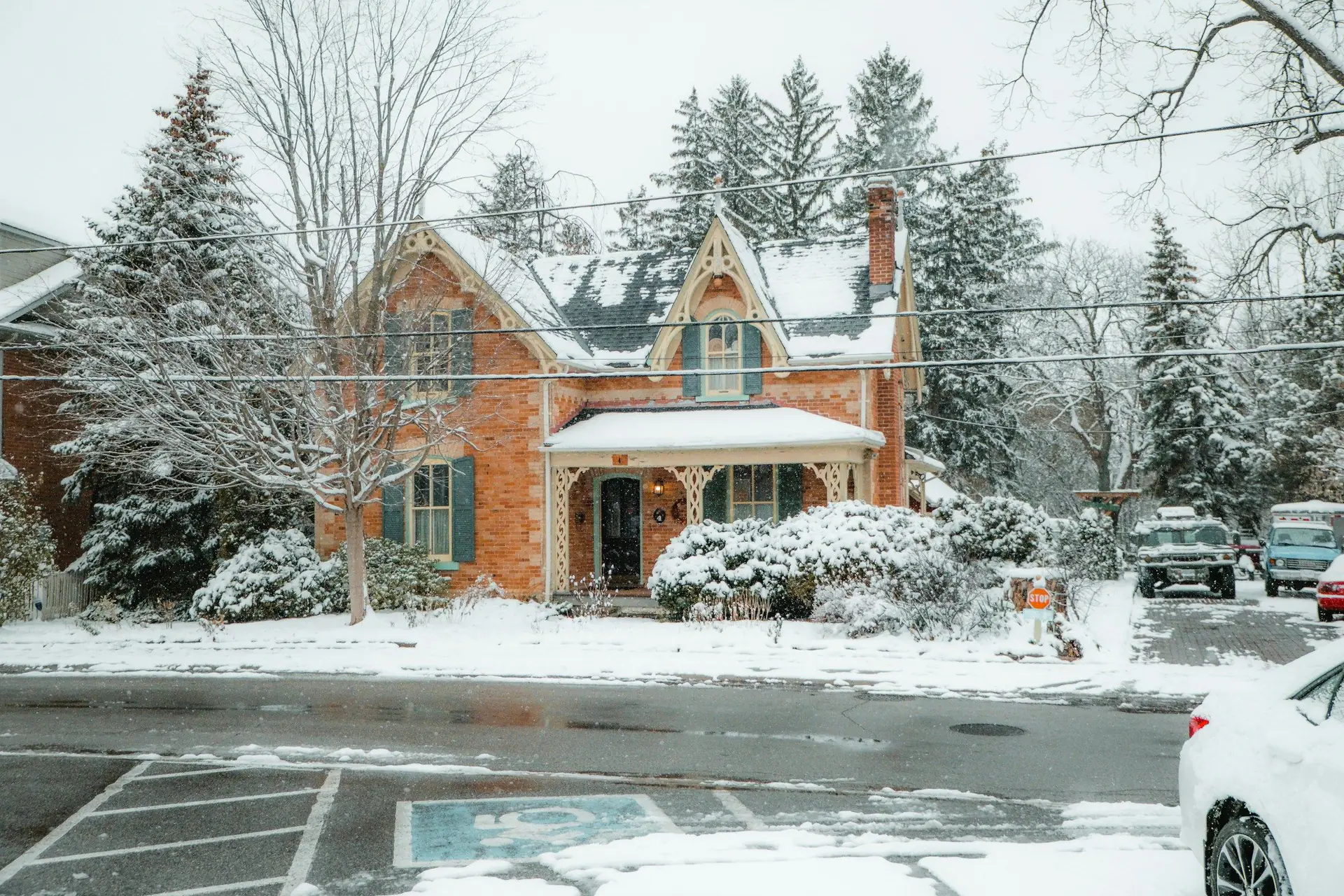 A red-brick Gothic Revival house with gingerbread trim after a snowfall