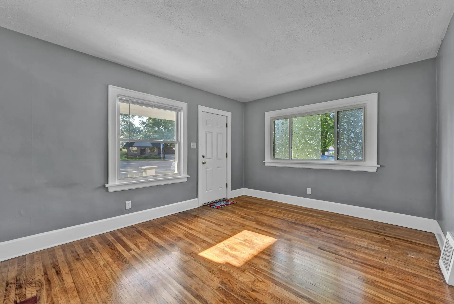 An empty bedroom with fresh grey walls and refinished hardwood floors