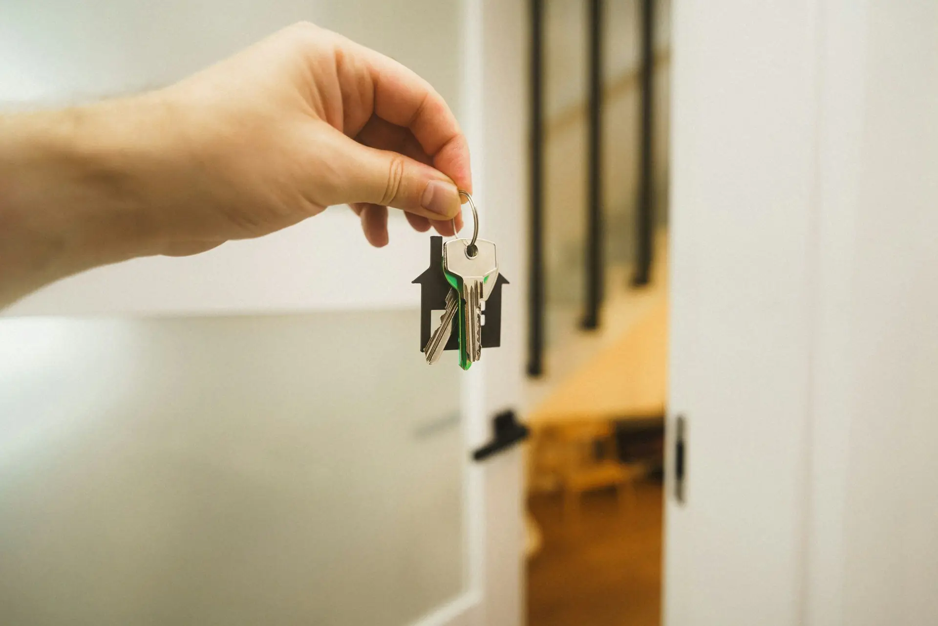 A hand holding up a new set of house keys at an open front door