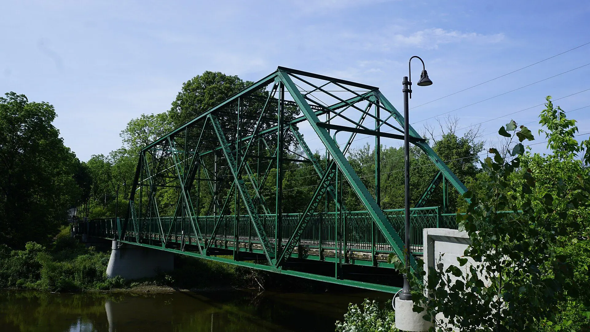 The green steel truss of the Meadowlily Bridge over the Thames in east London