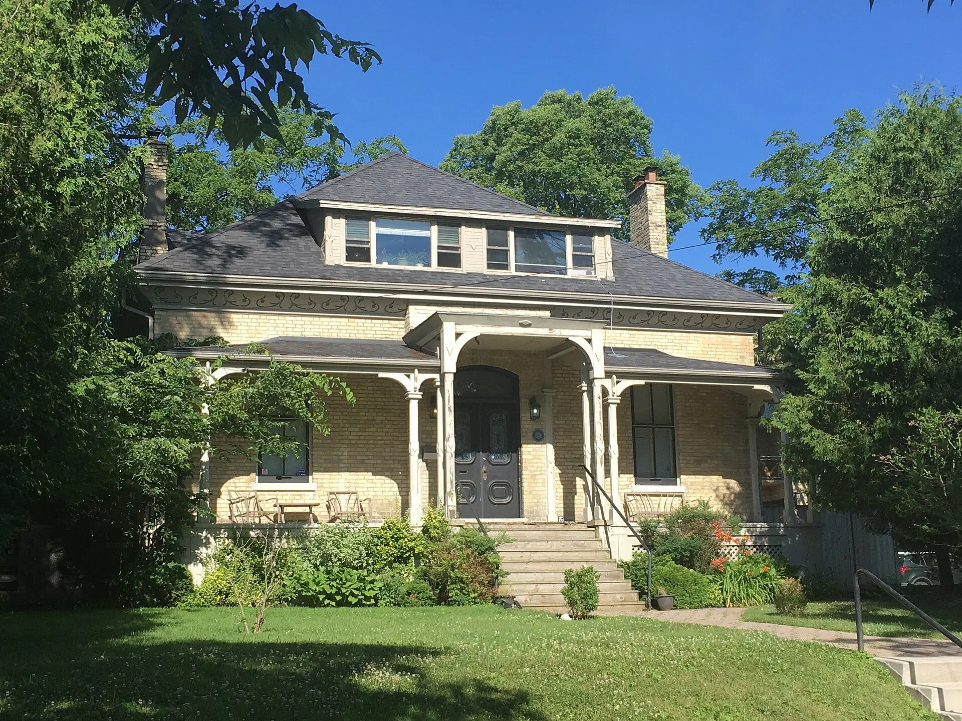 A buff-brick house with a deep white porch and carved brackets on High Street in Old South