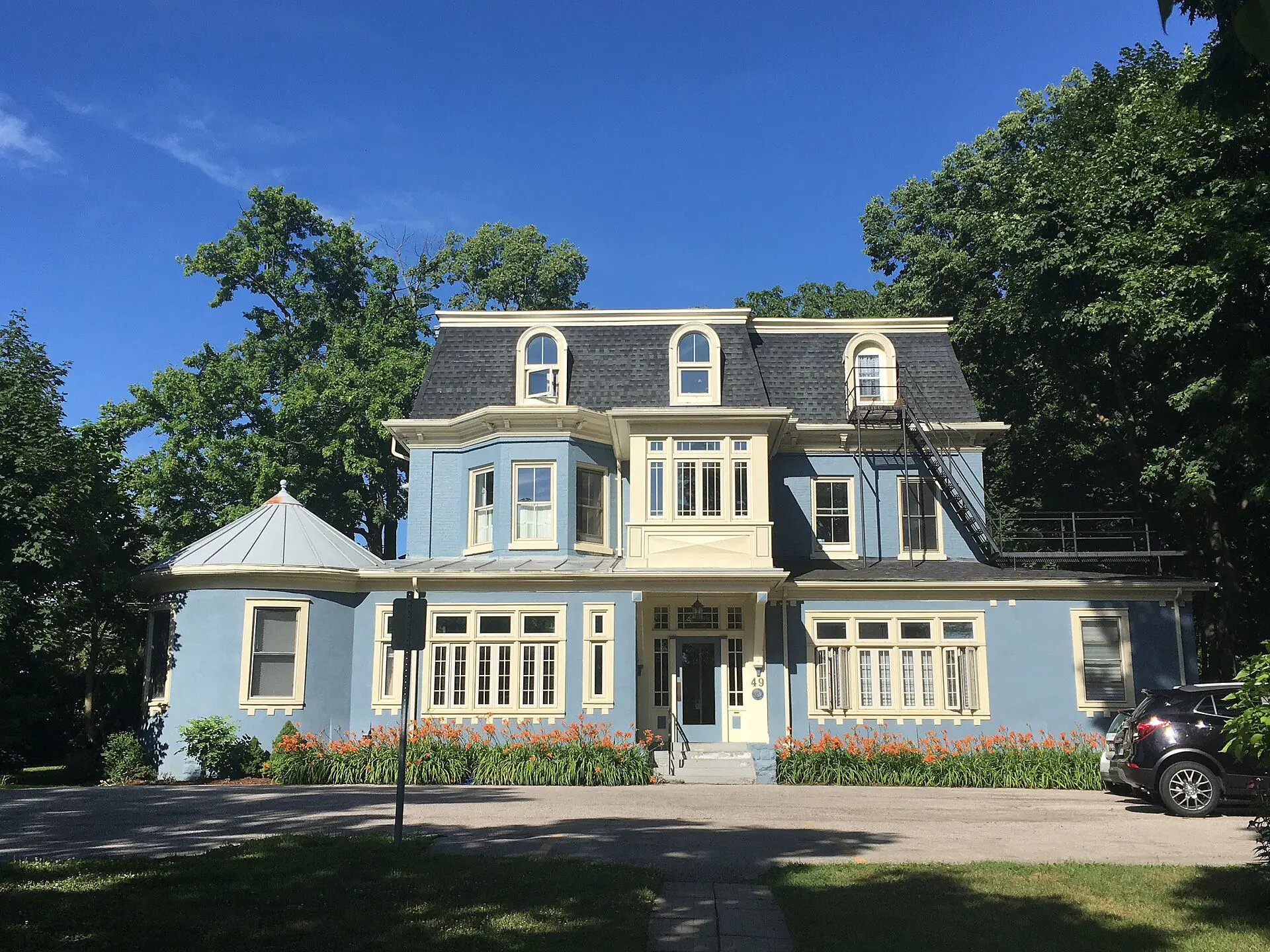 A blue Second Empire house with a mansard roof, divided into units, on Ridout Street South